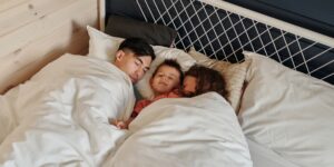 침대에서 잠든 아이의 상태를 주의 깊게 살피는 부모